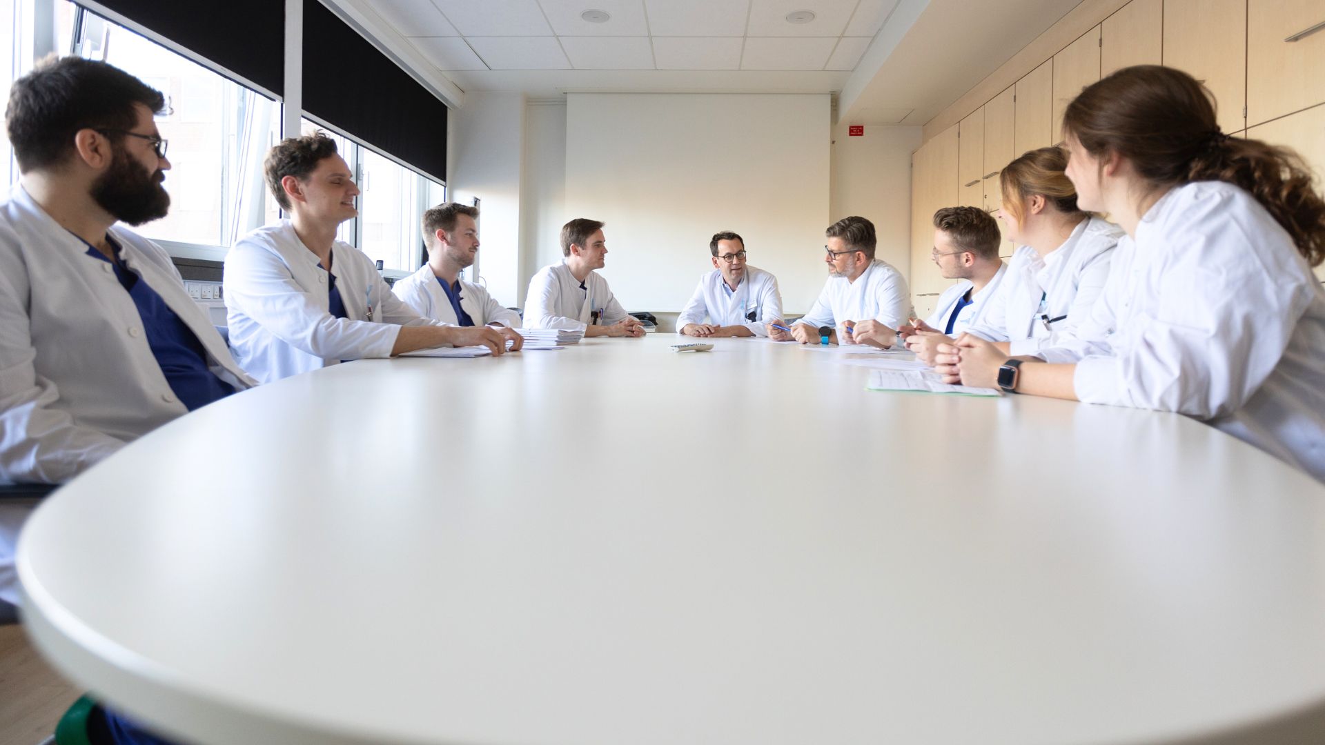 Das Ärzteteam der Klinik für Urologie am Marien Hospital Düsseldorf sitzt um einen runden Tisch während einer Besprechung.